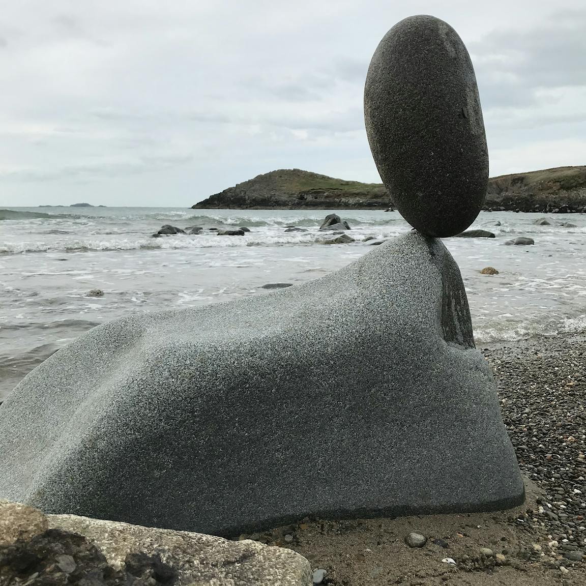 A large ovoid stone is balanced on the tip of a large rock.